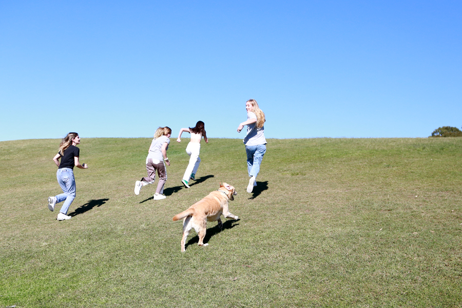 A group of young people laughing together running up a hill